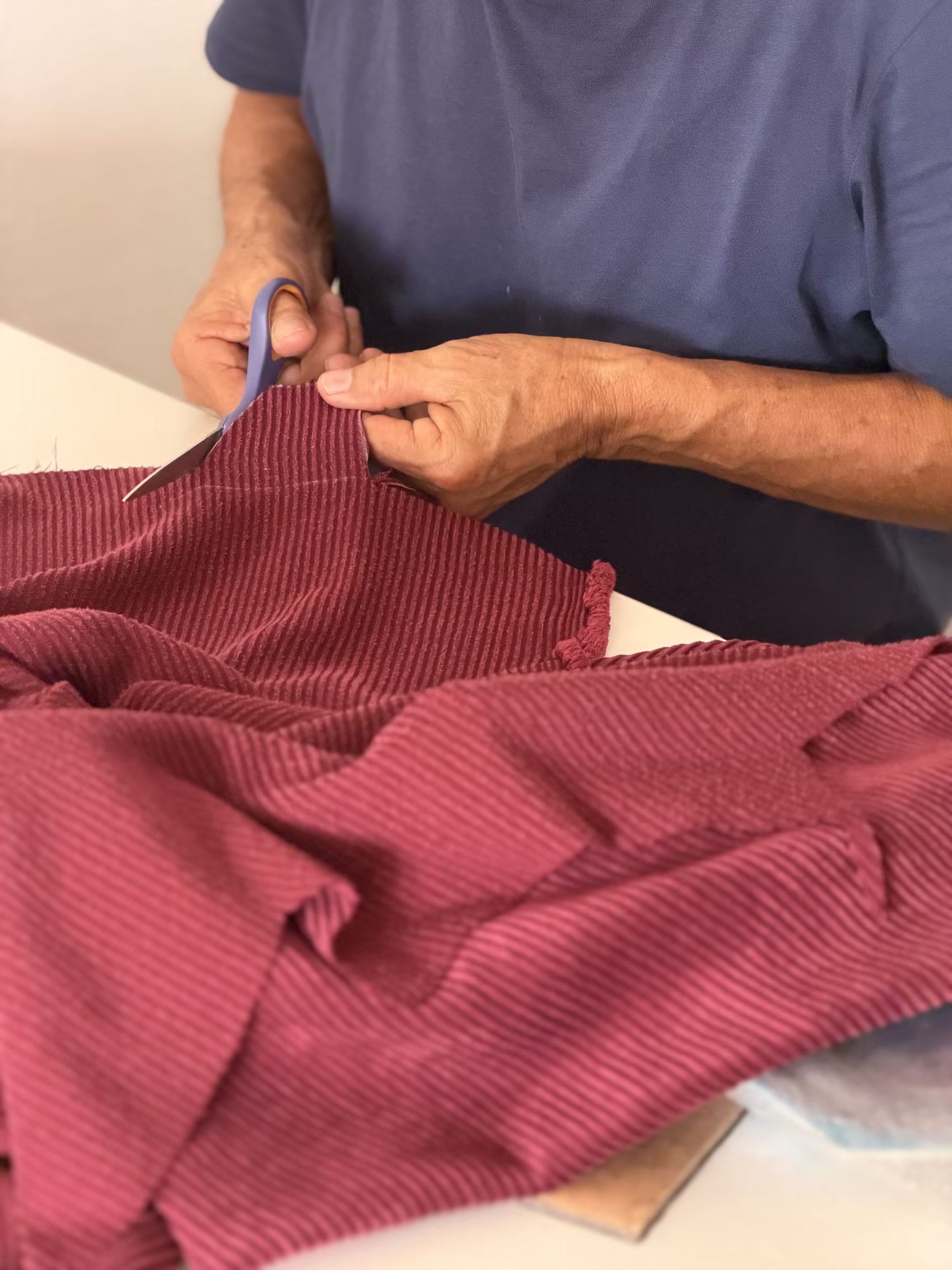 Manos cortando tela de pana para confeccionar un bolso Aguamiel